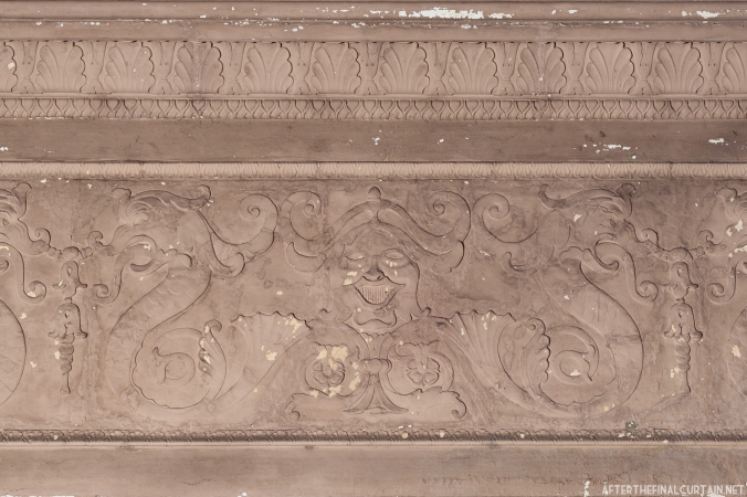 A face in plaster-work above the balcony.
